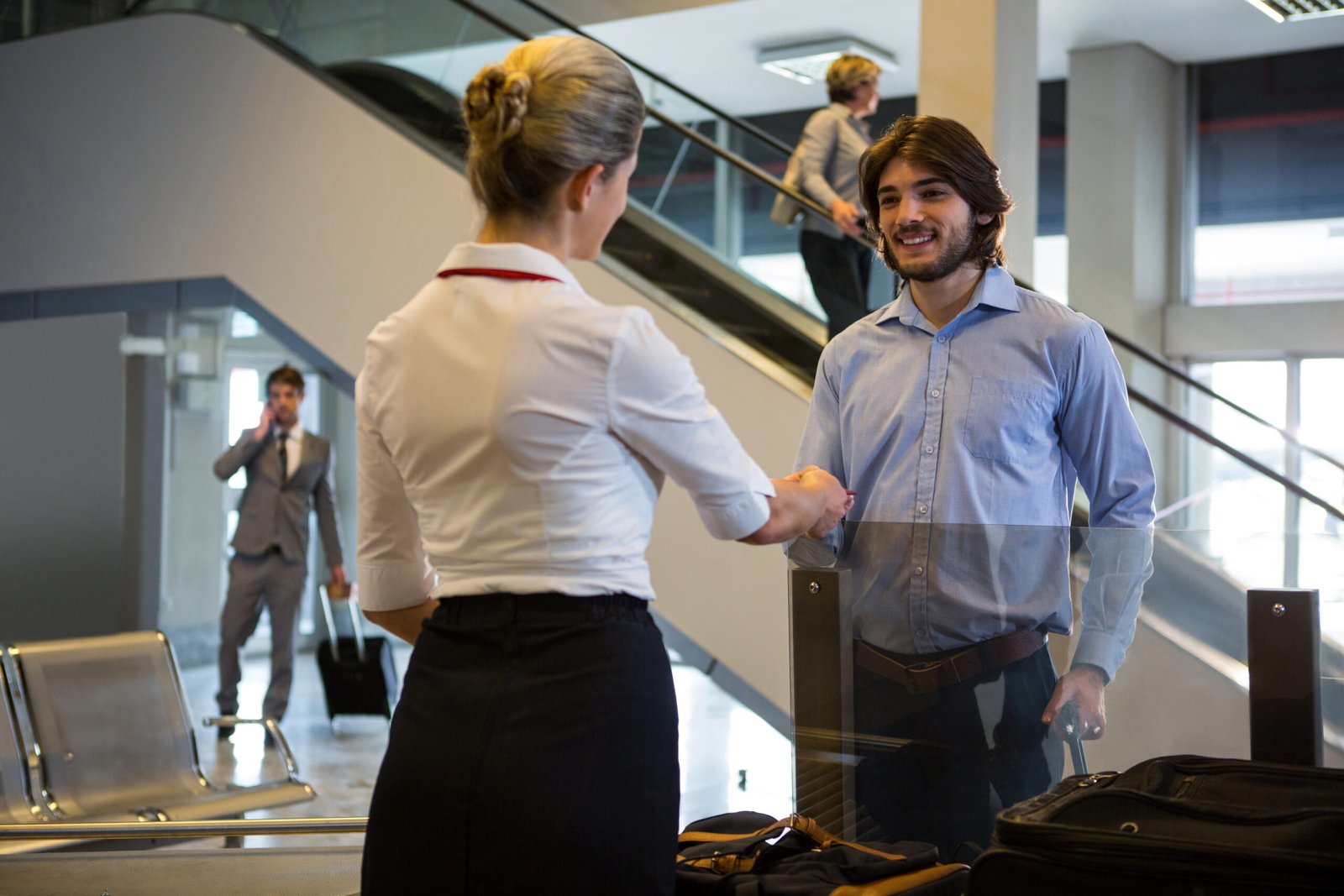 Female staff checking boarding pass of passengers at check-in counter in airport
